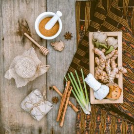 Natural Spa Ingredients herbal compress ball and herbal Ingredients for alternative medicine and relaxation Thai Spa theme with silk fabric on old wooden background.