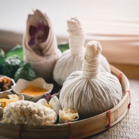 Spa massage wellness decorations setting on wood table. Thai spa massage traditional compress for hot massage and spa relaxing treatment of office syndrome. Massage for health concept.